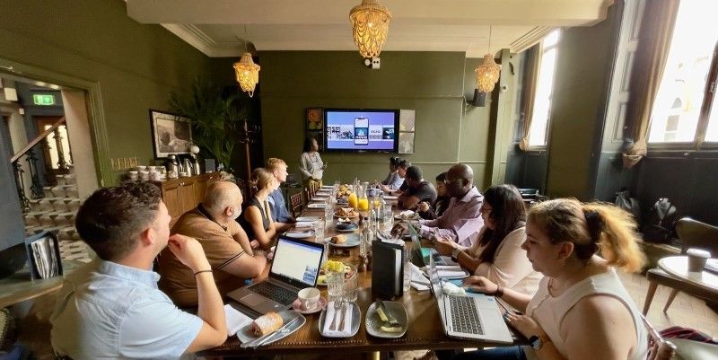 A group of people sat around a table whilst Professor Lisa-Dionne Morris presents.