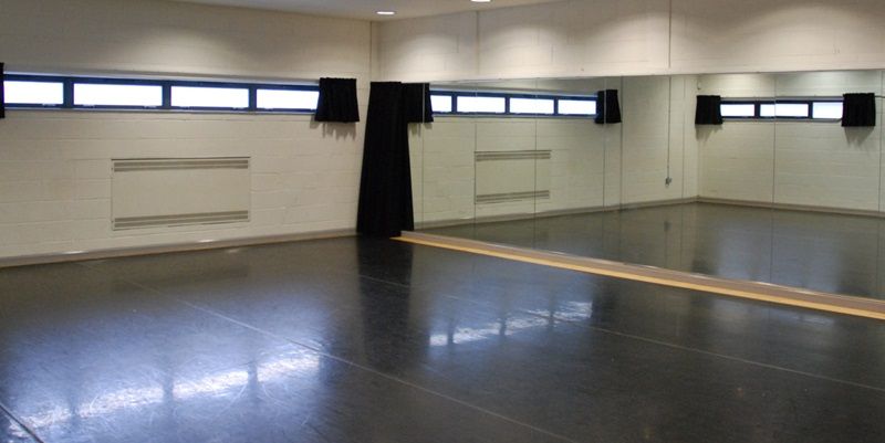 Inside a stage@leeds performance studio, showing a wide space with windows and curtains.