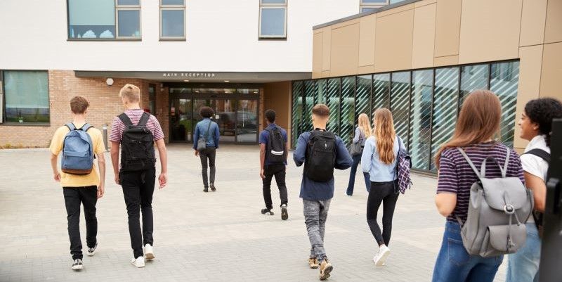 A group of students walk towards a school building main reception