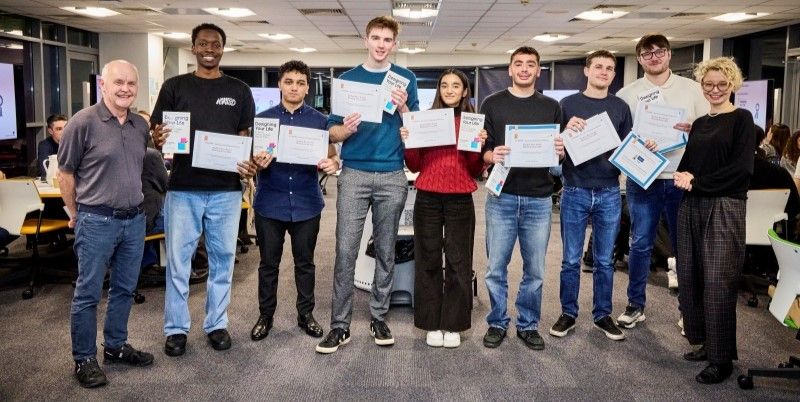 Two module leaders and the winning group of students pose for a photo with their certificates.